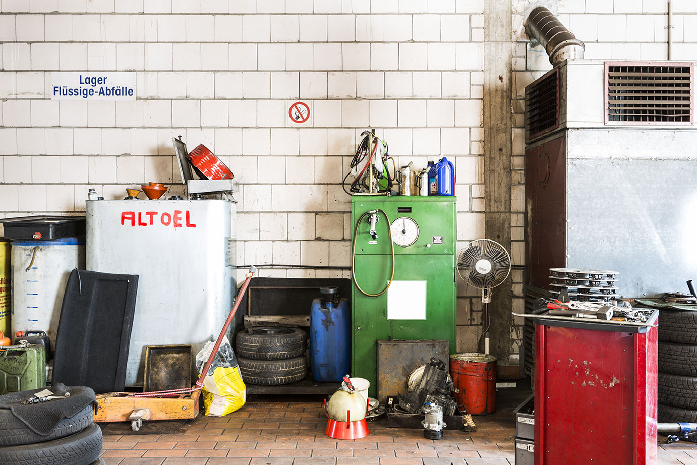 Auf dem Bild sieht man eine unaufgeräumte Garage mit einem großen Behälter gefüllt mit Altöl.